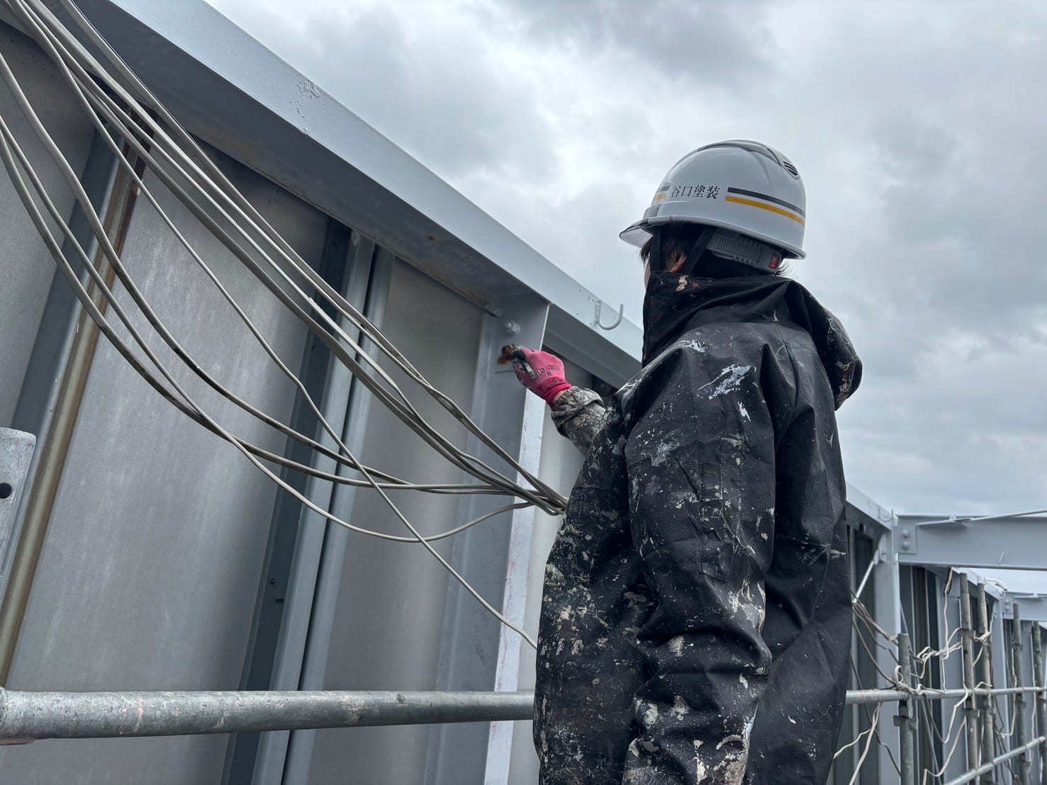 谷口塗装の職人が屋外の鉄骨構造物で塗装作業を行う様子